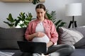 Happy pregnant woman holding laptop video call, talking with friends or relatives. Attractive future mother recording new video to Royalty Free Stock Photo