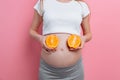 Beautiful pregnant woman with orange fruit on a pink background Royalty Free Stock Photo