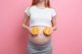 Beautiful pregnant woman with orange fruit on a pink background Royalty Free Stock Photo