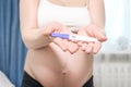 Happy pregnant woman holding pregnancy test with beautiful belly that pregnant girl has fetus inside. Young Mother waiting newborn