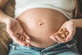 Happy pregnant woman at home eating fresh nuts - almonds, walnuts. Healthy pregnancy concept