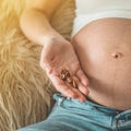 Happy pregnant woman at home eating fresh nuts - almonds, walnuts. Healthy pregnancy concept