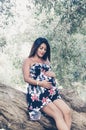 Happy pregnant woman hugging her stomach on the background of flowers,outdoor Royalty Free Stock Photo