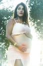 Happy pregnant woman hugging her stomach on the background of flowers,outdoor Royalty Free Stock Photo