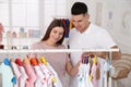 Happy pregnant woman with husband choosing baby clothes in store. Shopping concept Royalty Free Stock Photo