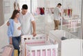 Happy pregnant woman and husband with shopping bags choosing crib in store Royalty Free Stock Photo