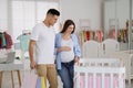 Happy pregnant woman and husband with shopping bags choosing crib in store Royalty Free Stock Photo