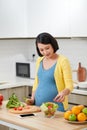 Happy pregnant woman on kitchen making healthy salad Royalty Free Stock Photo