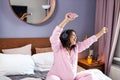 Happy pregnant woman listen to music with headphones while sitting on the bed at home Royalty Free Stock Photo