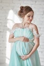 Happy Pregnant woman in long evening dress touching belly hands. Waiting the birth of a child, a woman in her eighth month Royalty Free Stock Photo