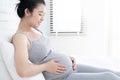 Happy pregnant woman lying on bed and touching her belly at home. Royalty Free Stock Photo