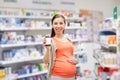 Happy pregnant woman with medication at pharmacy