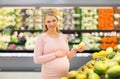 Happy pregnant woman with pear at grocery store Royalty Free Stock Photo