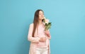 happy pregnant woman in pink t-shirt on blue background holding a bouquet of flowers Royalty Free Stock Photo