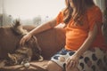 Happy pregnant woman playing with her cat pet sitting in kitchen sofa Royalty Free Stock Photo