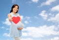 Happy pregnant woman with red heart touching belly Royalty Free Stock Photo