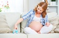Happy pregnant woman is resting at home on sofa and holding a bl Royalty Free Stock Photo