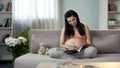 Happy pregnant woman reviewing catalogue, choosing furniture for childs room