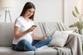 Happy pregnant woman shopping online, using smartphone and credit card at home, Royalty Free Stock Photo