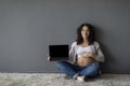 Happy Pregnant Woman Showing Laptop With Blank Screen While Sitting On Floor Royalty Free Stock Photo