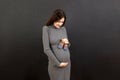 Happy pregnant woman showing small boots for a baby boy at Colored background. Future mother is waiting for a child Royalty Free Stock Photo