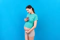 Happy pregnant woman showing small boots for a baby boy at Colored background. Future mother is waiting for a child Royalty Free Stock Photo