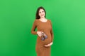 Happy pregnant woman showing small boots for a baby boy at Colored background. Future mother is waiting for a child Royalty Free Stock Photo