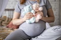 Happy pregnant woman sitting on bed at bedroom holding two cute bear toys awaiting twins baby Royalty Free Stock Photo