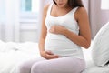 Happy pregnant woman sitting on bed at home Royalty Free Stock Photo