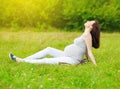 Happy pregnant woman sitting on the grass and enjoys summer Royalty Free Stock Photo