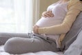 Happy pregnant woman touching belly sitting in bed at home, Close up Royalty Free Stock Photo