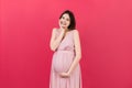 Happy pregnant woman touching her abdomen at Colored background. Future mother is wearing white underwear. Expecting of Royalty Free Stock Photo