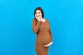 Happy pregnant woman touching her abdomen at Colored background. Future mother is wearing white underwear. Expecting of Royalty Free Stock Photo