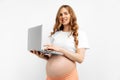 Happy pregnant woman using laptop, browsing internet and reading pregnancy blogs, on white background