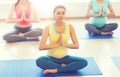 Happy pregnant women exercising yoga in gym