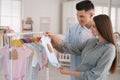 Happy pregnant woman with her husband choosing baby clothes in store. Shopping concept Royalty Free Stock Photo