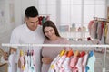 Happy pregnant woman with husband choosing baby clothes in store. Shopping concept Royalty Free Stock Photo