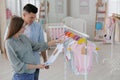 Happy pregnant woman with husband choosing baby clothes in store. Shopping concept Royalty Free Stock Photo