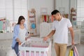 Happy pregnant woman and her husband with shopping bags choosing crib in store Royalty Free Stock Photo