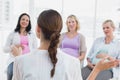 Happy pregnant women listening to gesturing doctor at antenatal class