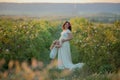 Happy pregnant woman with little daughter in a green tea rose garden