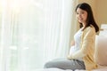 Happy pregnant young asian woman holding belly and look at camera with happiness smiley face. Young Asia pregnancy mother love her Royalty Free Stock Photo