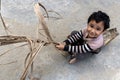 A happy preschool little kid having funny while playing climbs on a rope on yard equipment in daytime in summer. A little boy in a Royalty Free Stock Photo