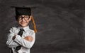 Happy Preschooler Boy in Eyeglasses and Graduation Hat over Blackboard with Copy Space. Happy Little Kid like Student in Smart