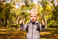 Happy preschooler showing OK sign in autumn park