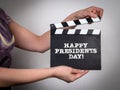 Happy Presidents Day. Woman in a colored dress holding a film clapper