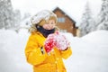 Happy preteen boy having fun playing with fresh snow during snowfall in european Alps. Child dressed in warm clothes, hat, hand