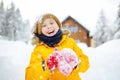 Happy preteen boy having fun playing with fresh snow during snowfall in european Alps. Child dressed in warm clothes, hat, hand