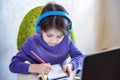 Happy preteen boy sitting on the couch or desk while using a laptop and headphones at home. Online chatting with his school Royalty Free Stock Photo