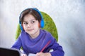 Happy preteen boy sitting on the couch or desk while using a laptop and headphones at home. Online chatting with his school Royalty Free Stock Photo